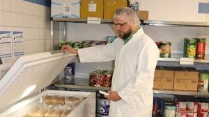 Ein Lebensmittelkontrolleur öffnet eine Kühltruhe in einem Gastronomiebetrieb