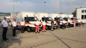 Mitarbeiter von Feuerwehr und DRK stehen vor den neuen Einsatzfahrzeugen