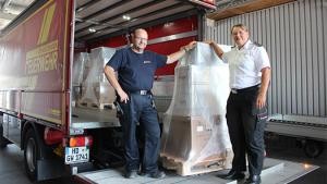 Zwei Personen laden Pakete in einen Feuerwehr-LKW