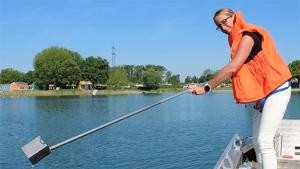 Hygienekontrolleurin bei der Entnahme einer Wasserprobe im See