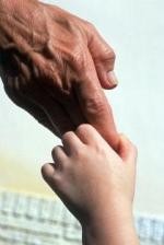 Kind hält die Hand eines Erwachsenen