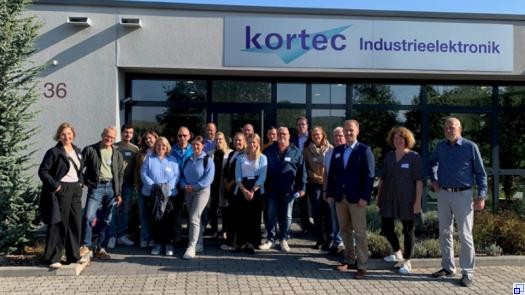 Eine Gruppe von Menschen steht vor dem Eingangsbereich des Haupthauses der kortec Industrieelektronik GmbH.