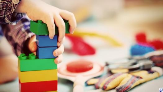 Kinderhand stapelt große Lego-Steine aufeinander