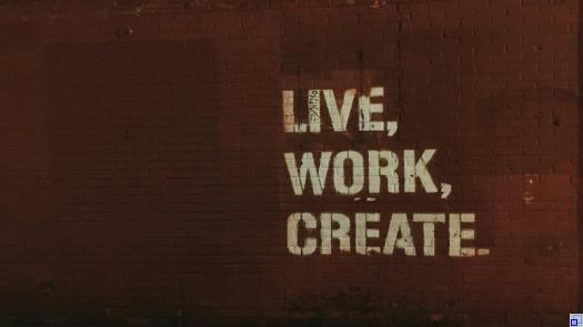 rote Backsteinmauer; darauf ein Graffiti mit den Worten "Live, Work, Create".