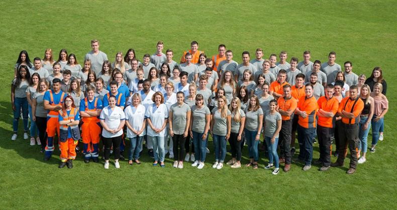 Gruppenfoto mit allen Azubis auf grünem Rasen