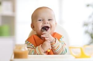Baby leckt Löffel mit Brei ab