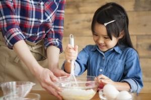 Mutter und Kind rühren gemeinsam Kuchenteig