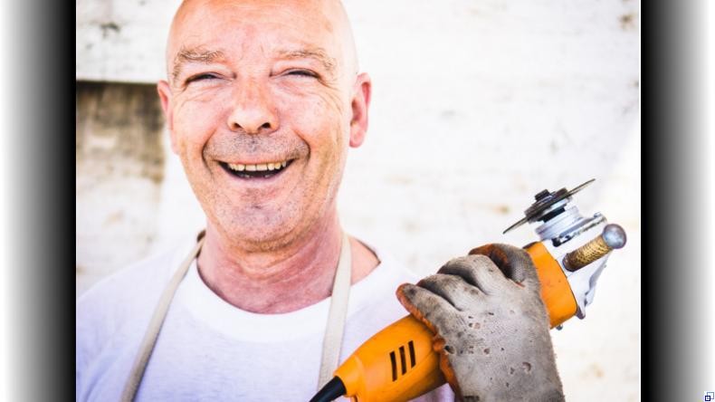 Lachender älterer Mann mit Werkzeug in der Hand