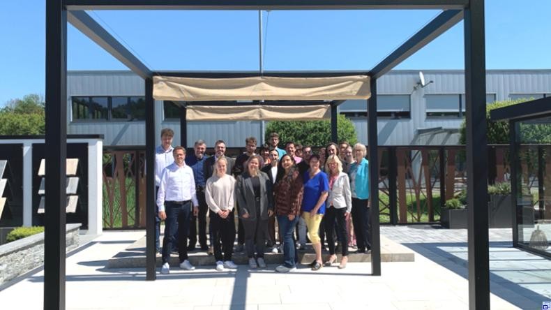 Bild: Rhein-Neckar-Kreis Eine Gruppe Menschen steht auf einer sonnenbeschienenen Terrasse.
