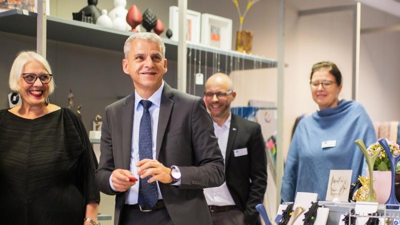 Bild: IHK Rhein-Neckar Der Staatssekretär geht gemeinsam mit zwei Frauen und einem Mann durch einen Laden, in dem Designobjekte ausgestellt sind. Alle Menschen auf dem Foto lächeln.