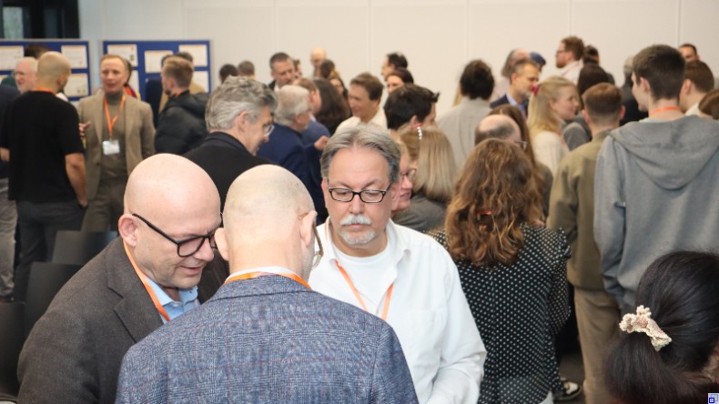 Bild: food.net:z Drei Männer unterhalten sich. Im Hintergrund zahlreiche weitere Menschen im Gespräch.