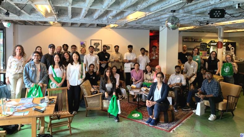 Bild: Welcome Center Rhein-Neckar Eine größere Gruppe junger Menschen verschiedener Ethnien steht bzw. sitzt in einem Café. Sie haben sich für das Gruppenfoto aufgestellt.