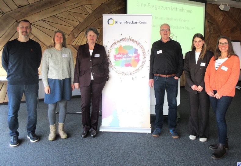 Referenten der Fachfortbildung Gruppenbild der Referenten vor holzvertäfeltem Sitzungssaal. mittig steht das Roll-up mit dem bunten Logo "Inklusion im Kreis".