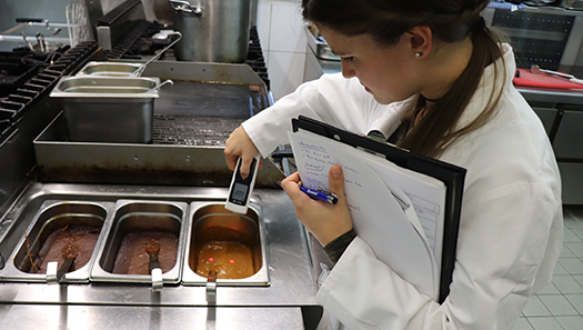 Mitarbeiterin nimmt Lebensmittelproben in einer Restaurantküche