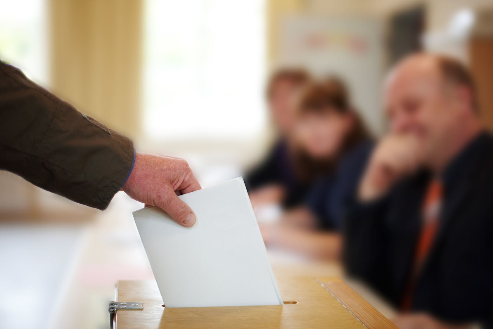 Mann wirft Stimmzettel in Wahlurne