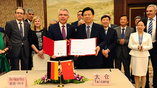 Landrat und chinesischer Bürgermeister halten die Partnerschaftsurkunde in den Händen.