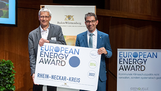 2 Personen halten ein Schild mit dem Titel Europaen Energy Award in den Händen 