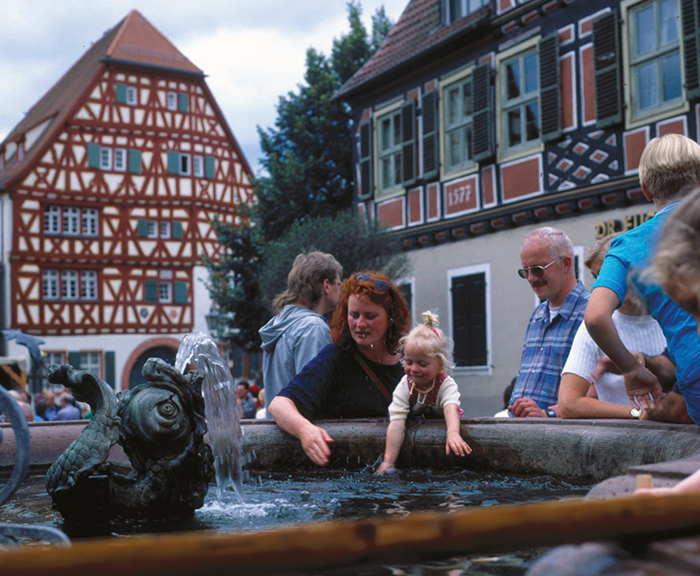 Menschen am historischen Brunnen in der Altstadt von Ladenburg