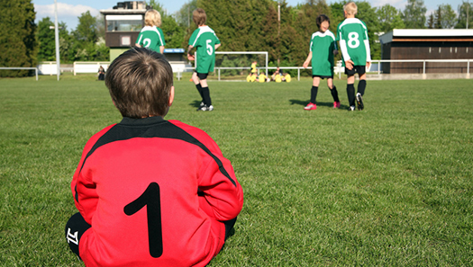 Junger Fußballspieler sitzt am Spielfeldrand