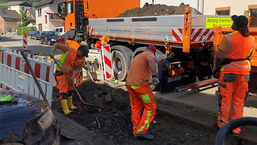 3 Arbeiter der Straßenmeisterei bei Instandsetzungsarbeiten an einer Straße