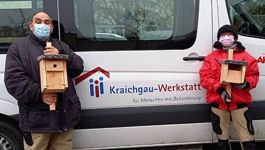 Zwei Personen halten jeweils einen Nistkasten aus Holz in den Händen.