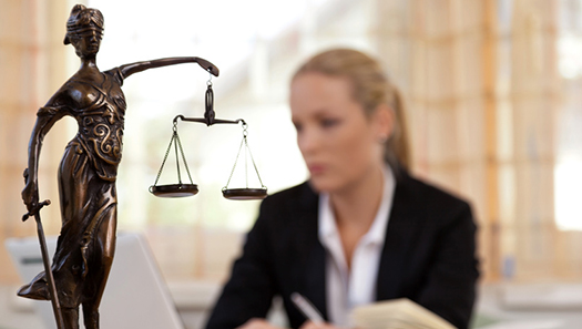 Symbolbild Symbolbild zeigt im Vordergrund eine bronzene Justitia-Statue und im Hintergrund leicht verschwommen eine Frau