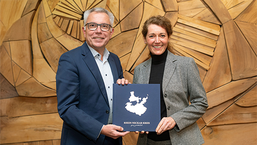 Landrat und die Vertreterin des Verlags halten das Buch in den Händen