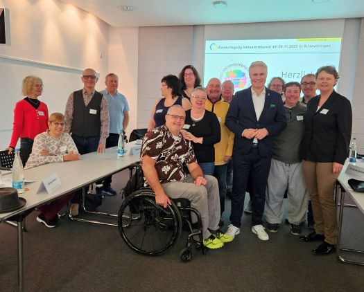 Beirat mit Schwetzinger Oberbürgermeister Matthias Steffan Beiratsmitglieder und Behindertenbeauftragte stehen im Tagungsraum in einer kleinen Gruppe um HerOberbürgermeitster Matthias Steffan aus Schwetzingen.