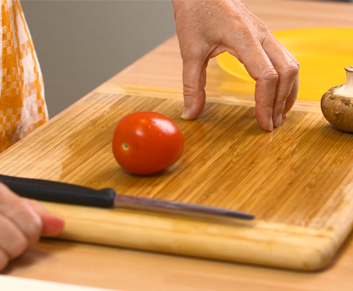 Eine Tomate wird mithilfe des Tunnelgriffs geschnitten