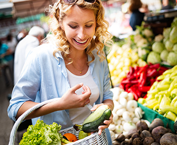 Frau kauft an einem Marktstand Gemüse