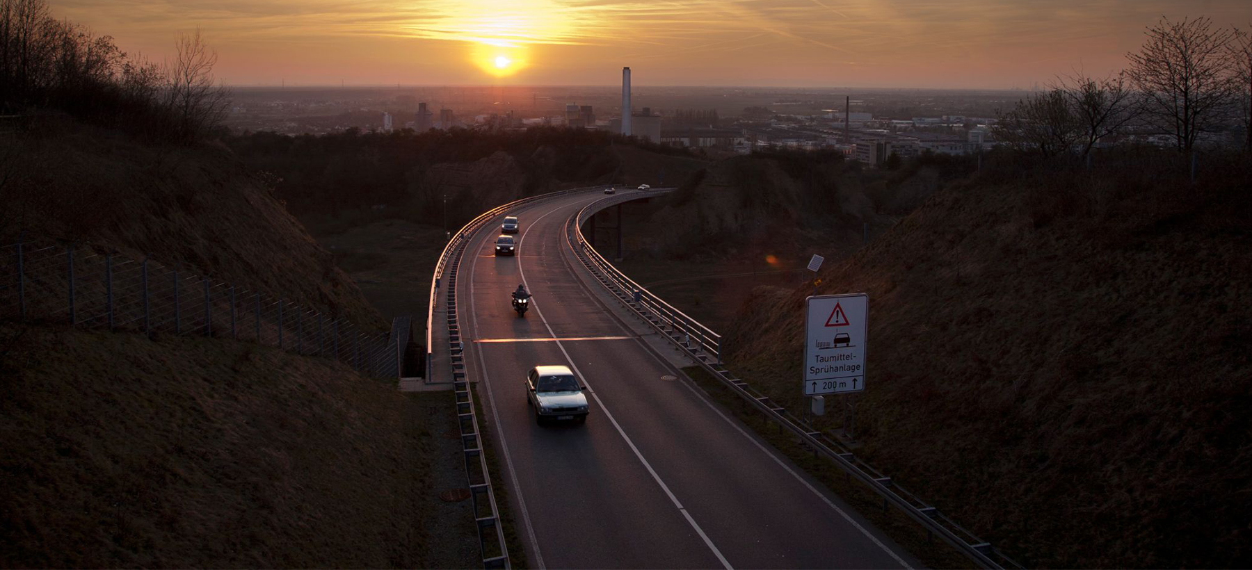 Straße in die industriell geprägte Rheinebene im Abendlicht