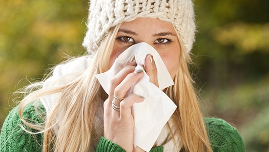 Junge Frau putzt sich die Nase in ein Taschentuch
