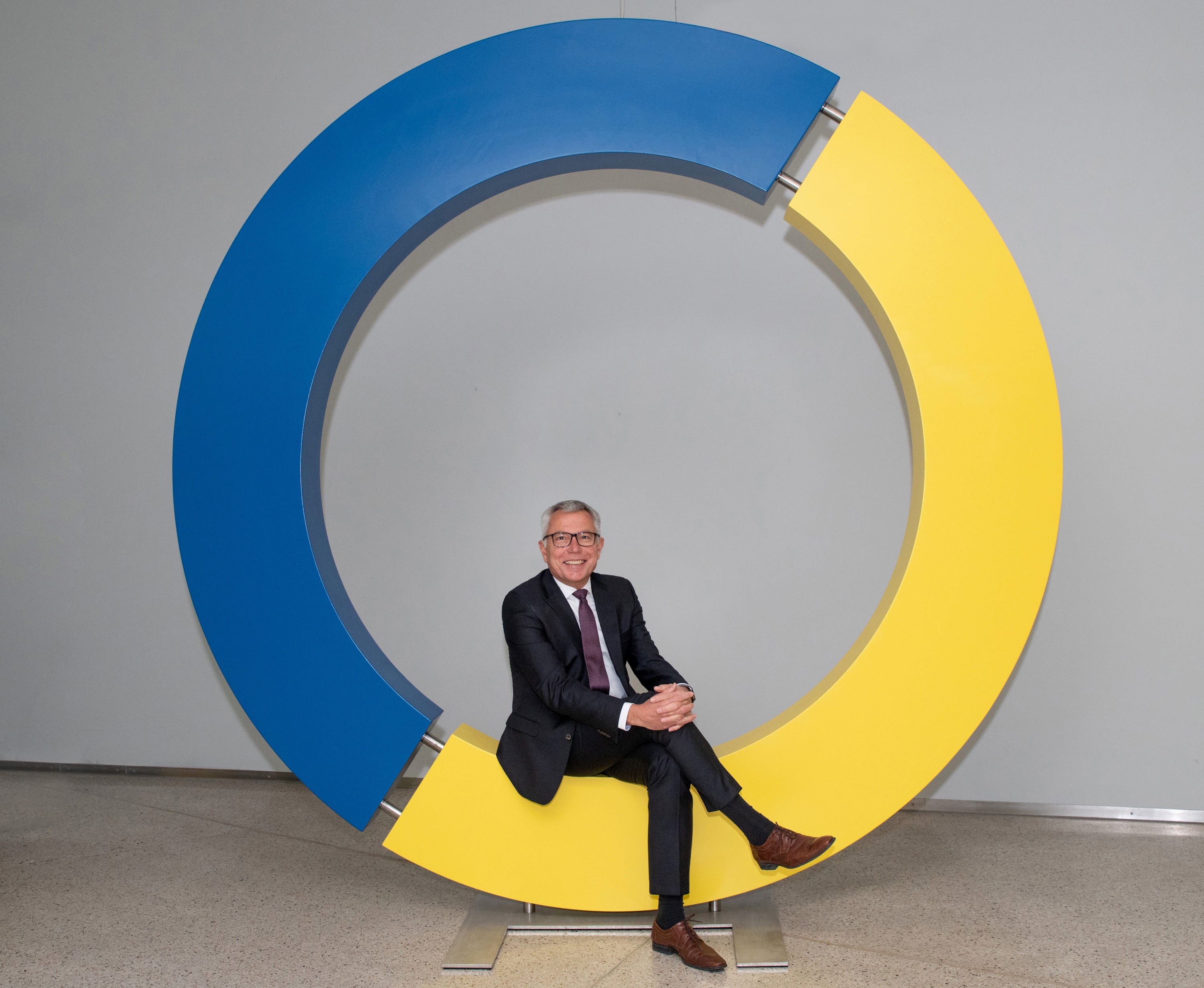 Landrat Stefan Dallinger sitzt in einem aus Holz gestalteten Kreislogo