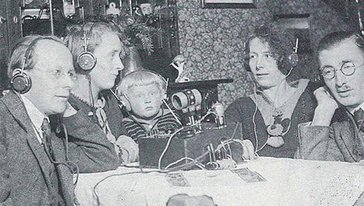 Historisches Foto einer Familie in den 1920er Jahren, die Radio mit Kopfhörern hört.