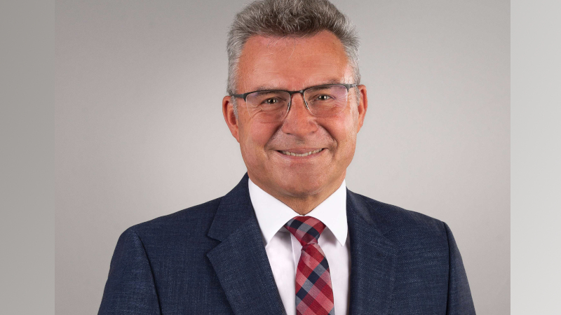 Porträtaufnahme des Landkreistagspräsidenten Dr. Achim Brötel. Er hat graues kurzes Haar und trägt eine Brille. Er trägt Jackett, ein weißes Hemd und eine rot-blau-karierte Krawatte.
