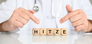 (Foto: HNFOTO / stock.adobe.com) Arzt zeigt auf Buchstabenwürfel, die das Wort HITZE bilden