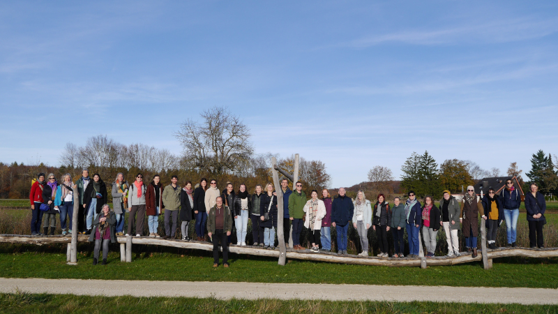 viele Menschen stehen in grüner Landschaft in einer Reihe