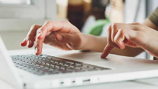 Person tippt auf Tastatur eines Notebooks