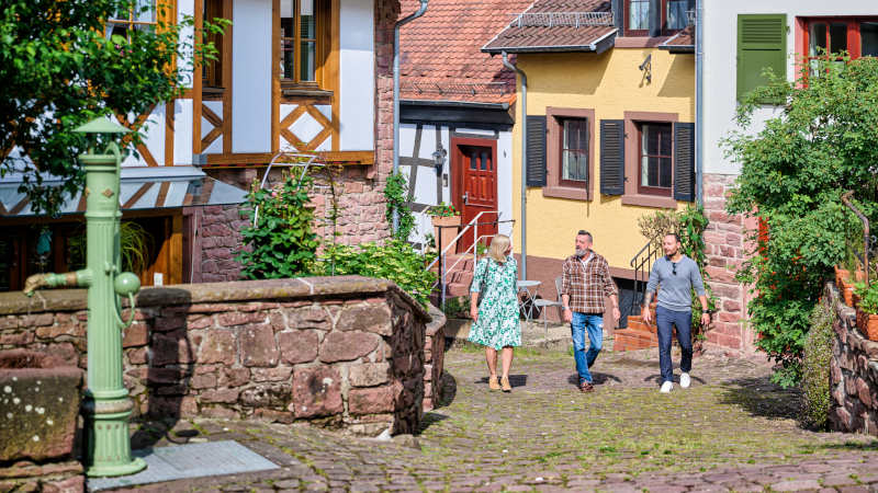 Drei Menschen gehen durch eine hübsche Altstadt