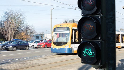 Ampel zeigt grünes Radsymbol, dahinter ist eine Straßenbahn und Autos zu sehen